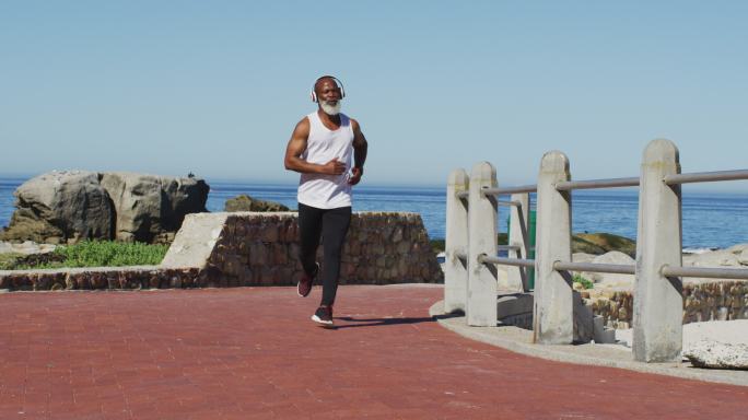一位美国黑人老人在海边的公路上跑步