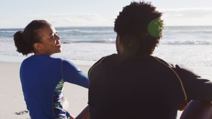一对非洲裔美国夫妇坐在沙滩上聊天