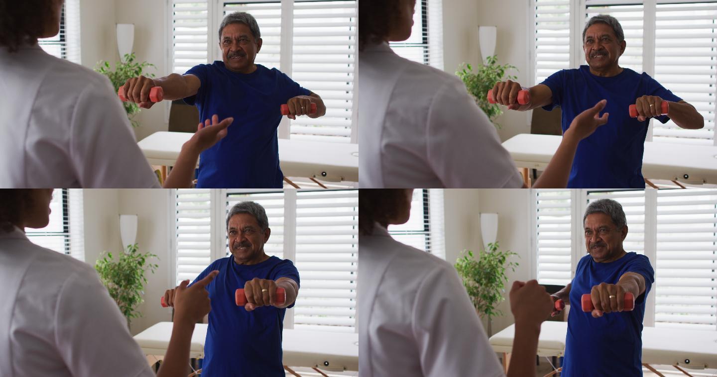 混血女性物理治疗师帮助老年男子使用哑铃锻炼