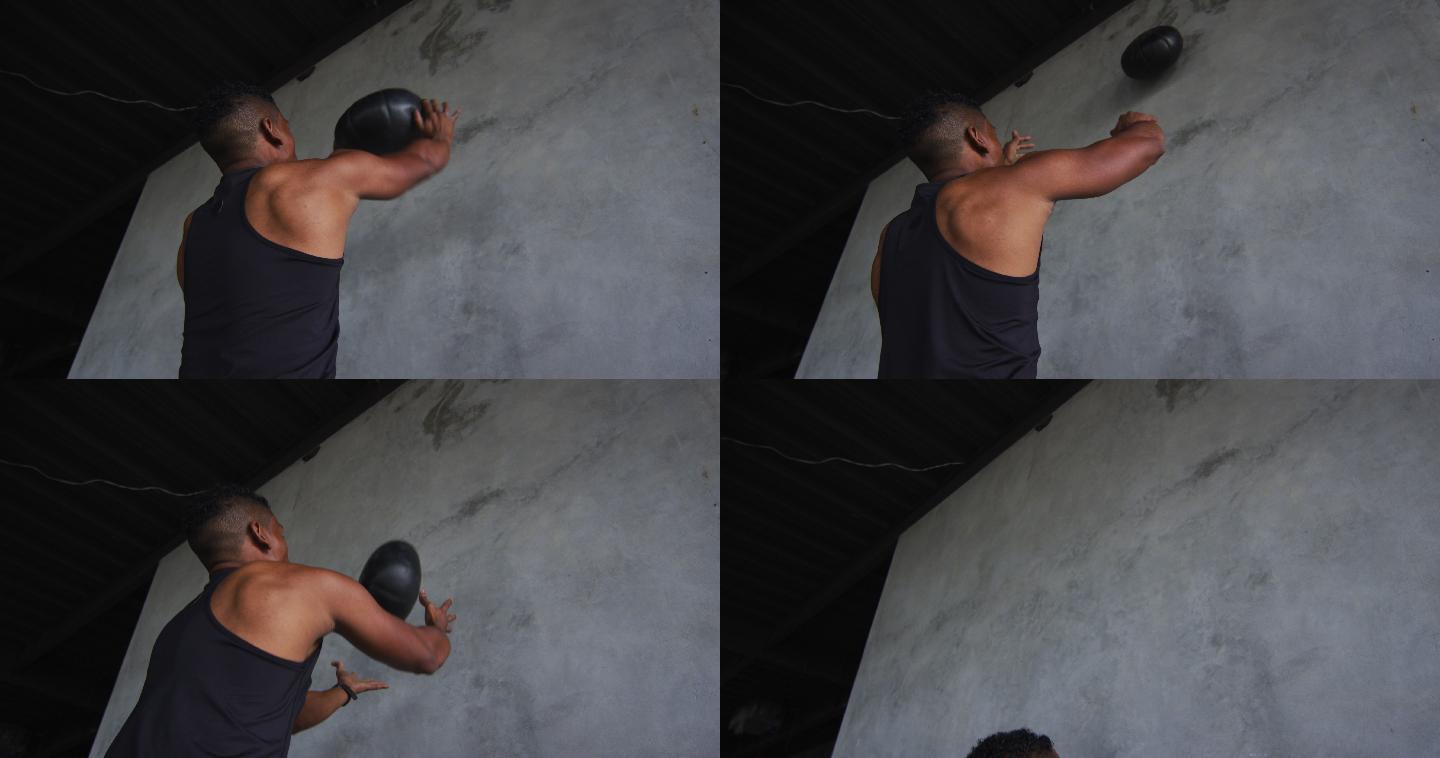 一个非裔美国人在一个空的城市建筑里用实心球锻炼