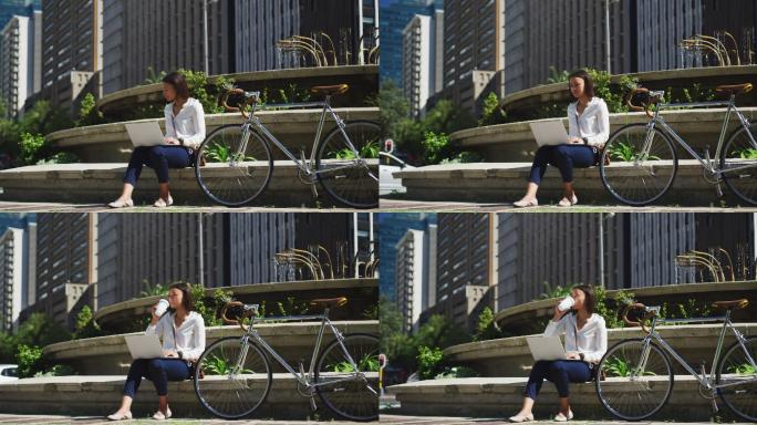 非裔美国妇女骑自行车用笔记本电脑喝咖啡在城市公园