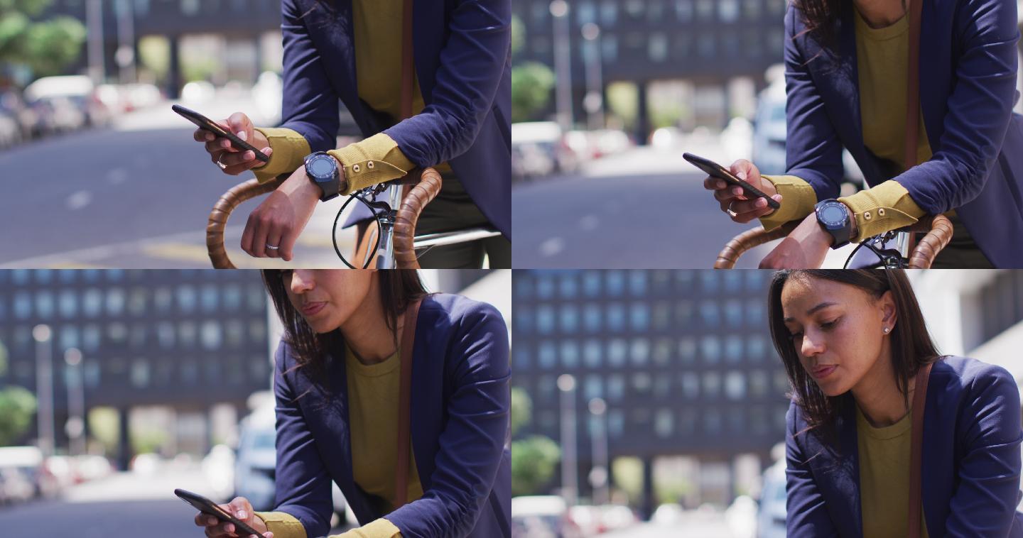 非裔美国妇女倚着自行车在街上使用智能手机