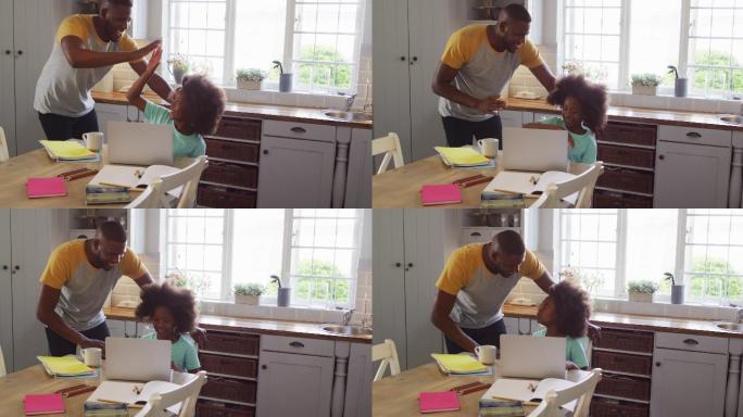 非裔美国人的女儿和她的父亲在餐桌上一起使用笔记本电脑