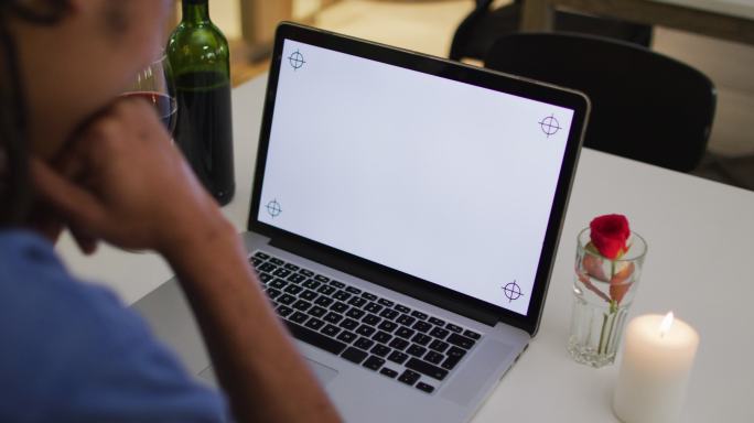混血男子有一个浪漫的晚餐在视频聊天使用笔记本电脑与拷贝空间