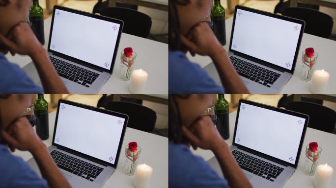 混血男子有一个浪漫的晚餐在视频聊天使用笔记本电脑与拷贝空间