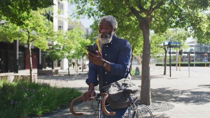 非裔美国老人骑着自行车在路上使用智能手机