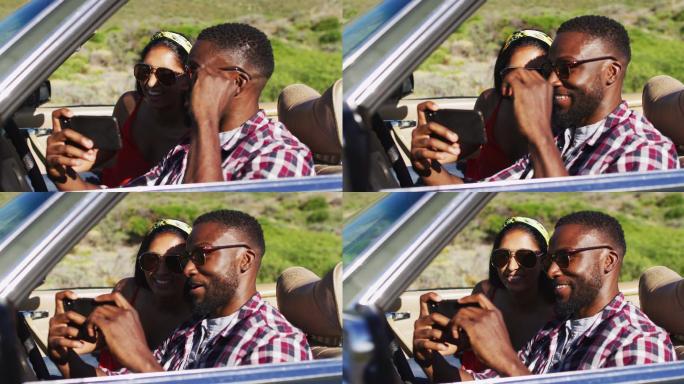 一对非洲裔美国夫妇在路上坐在敞篷车里使用智能手机