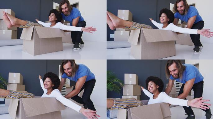 一个白人男人推着他的妻子坐在新公寓的纸箱里