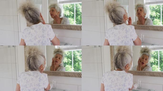 白人老年妇女在家里照镜子时摸自己的脸