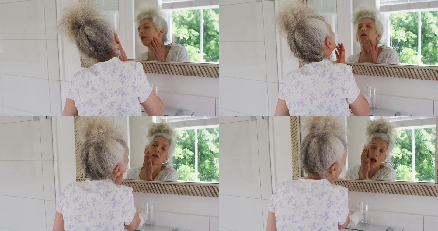 白人老年妇女在家里照镜子时摸自己的脸
