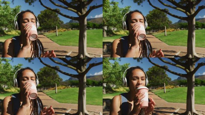 一位戴着耳机坐在公园里喝咖啡的非裔美国妇女