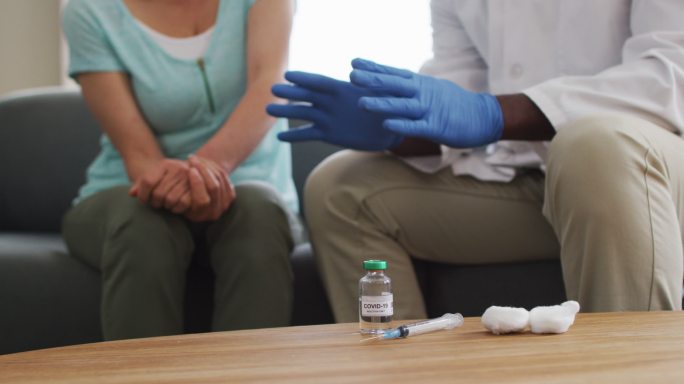 非裔美国男医生在注射covid-19疫苗前与女患者交谈的中段