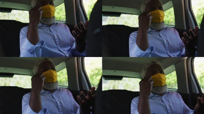 非裔美国老人戴着口罩坐在车里用智能手机聊天