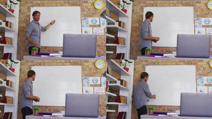 白人男教师在学校的教室里一边教化学一边看着笔记本电脑