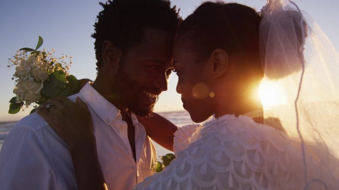 相爱的非裔美国人结婚了，夕阳西下时在海滩上看别人