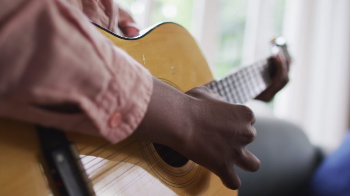 近距离观察非洲裔美国妇女在家里弹吉他
