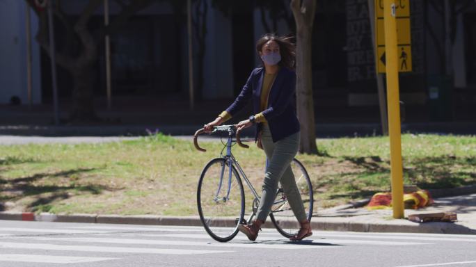 非洲裔美国妇女戴着口罩骑着自行车过马路