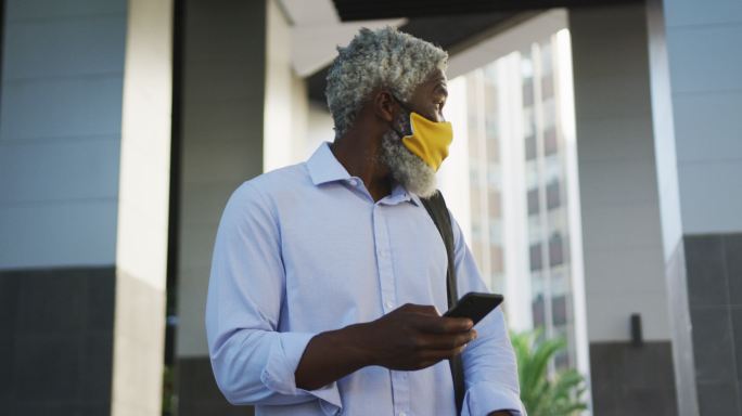 非裔美国人高层戴着口罩，用智能手机在公司园区四处张望