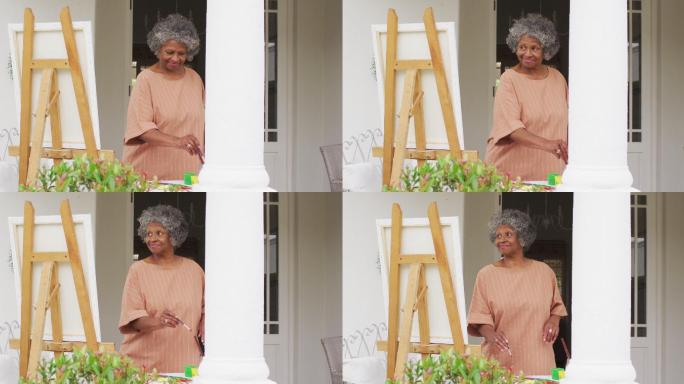 一位高级非洲裔美国妇女站在房子的门廊上作画