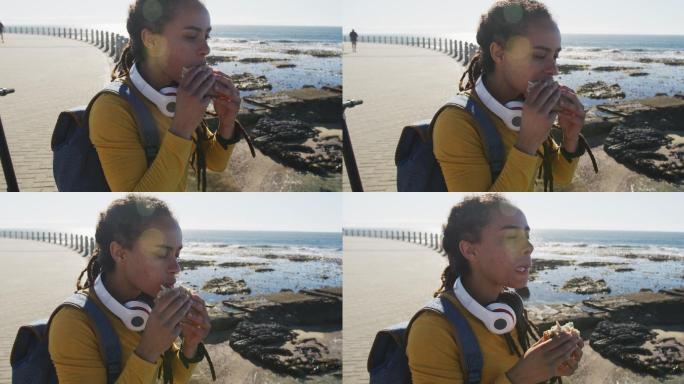 非裔美国妇女坐在海边散步吃三明治