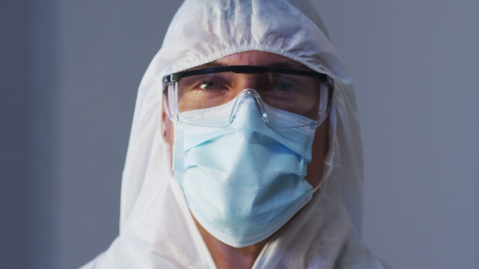 白人男性医务工作者的肖像，穿着防护服，戴着口罩和安全眼镜
