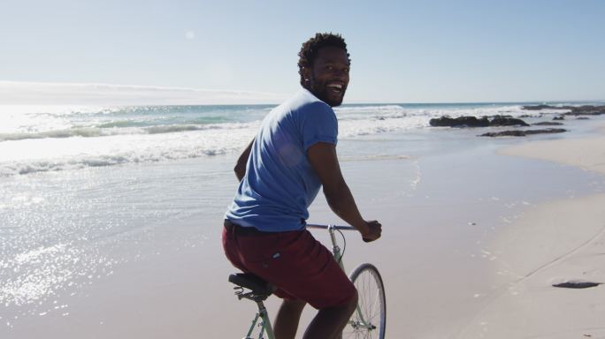 非洲裔美国人微笑和骑自行车在海滩上