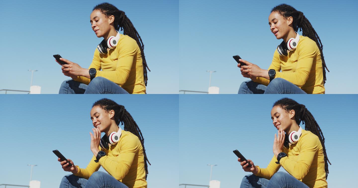 一名非裔美国妇女坐在海边散步时使用智能手机