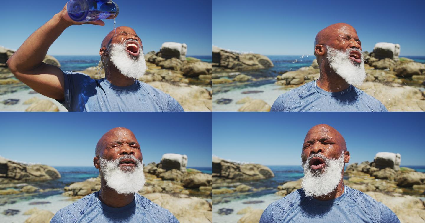 一位年长的非洲裔美国人在海边的岩石上练习往脸上浇水