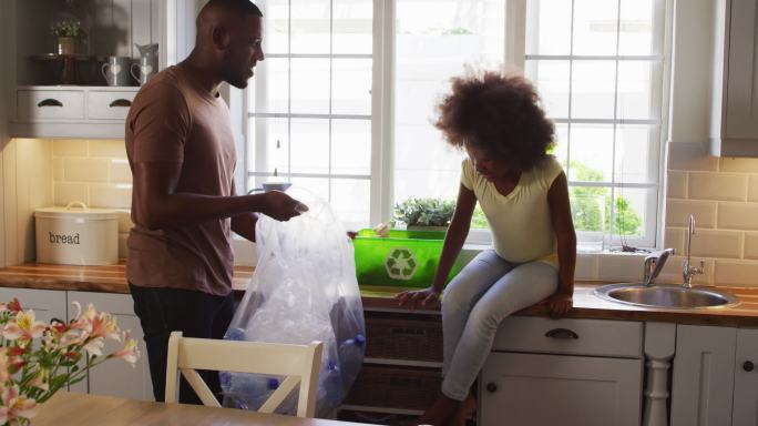 非洲裔美国人的女儿和她的父亲整理垃圾，在厨房里击掌