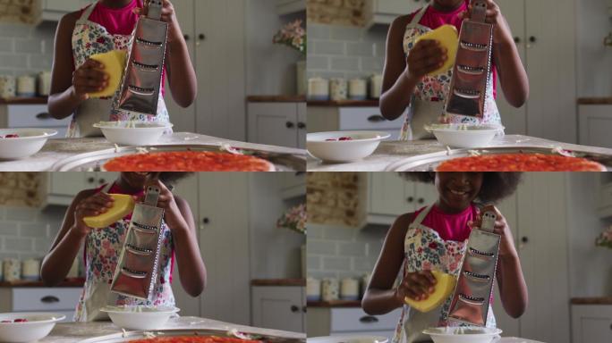 非裔美国女孩在厨房做披萨把奶酪磨碎