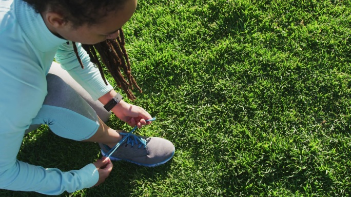 非裔美国妇女穿着运动服在公园里系鞋带