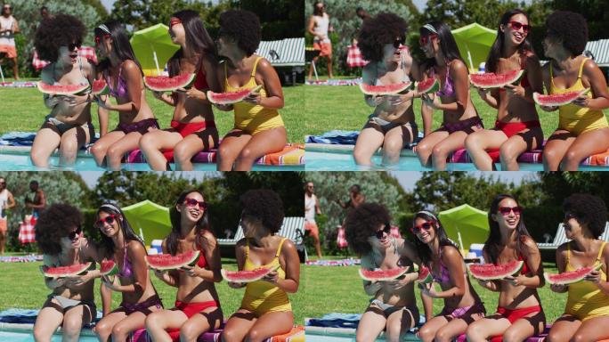 一群不同的女孩拿着西瓜坐在游泳池边聊天