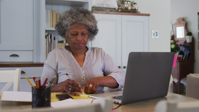 一位资深的非裔美国妇女在家里的笔记本电脑上贴便条