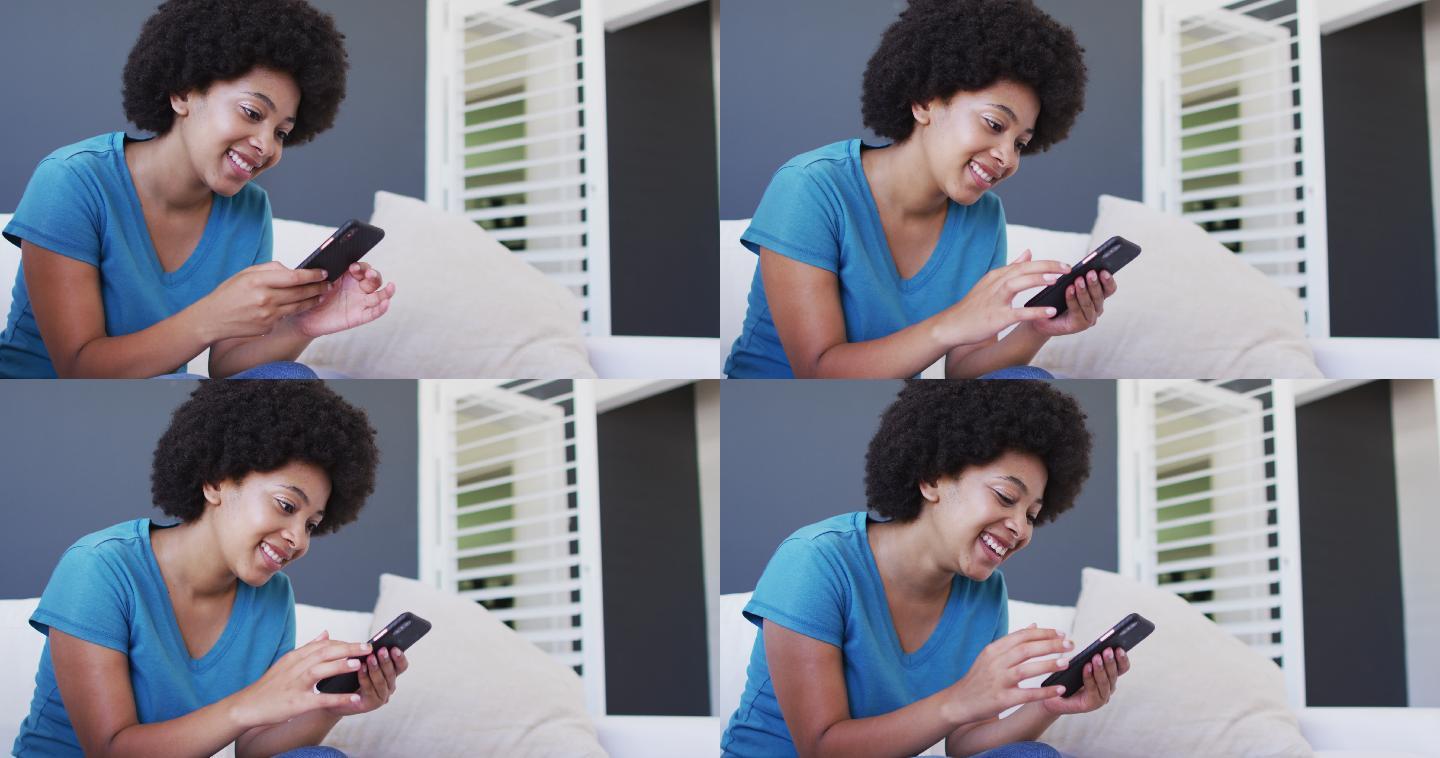 一位非裔美国女性坐在家里的沙发上使用智能手机