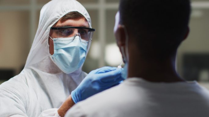 穿着防护服的白人男性医务工作者在实验室从病人身上提取dna拭子样本