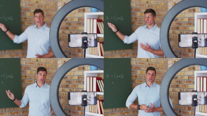 白人男性数学老师站在黑板前给摄像机上在线课