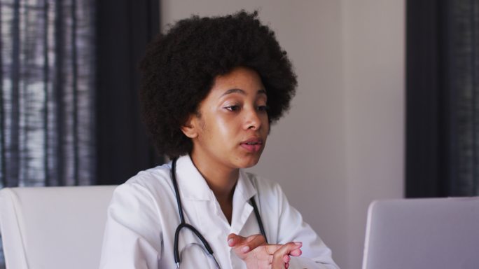 非裔美国女医生坐在家里用笔记本电脑进行视频通话