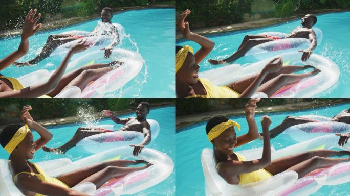 快乐的非裔美国夫妇躺在游泳池里的充气玩具上，微笑着互相溅起水花