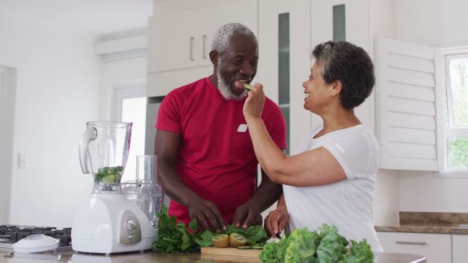 高级非洲裔美国男女在家里准备水果和蔬菜保健饮料