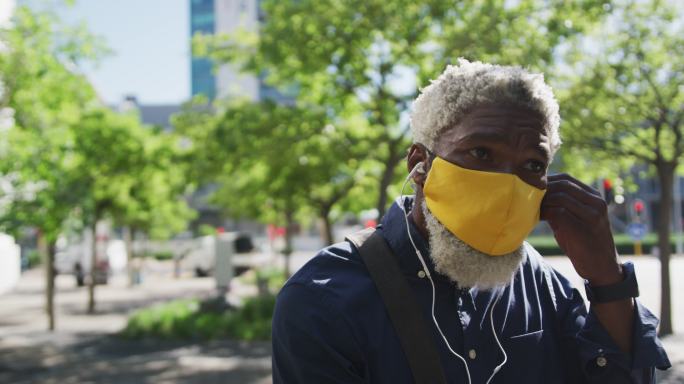 非洲裔美国老人戴着口罩戴着耳机在路上的特写