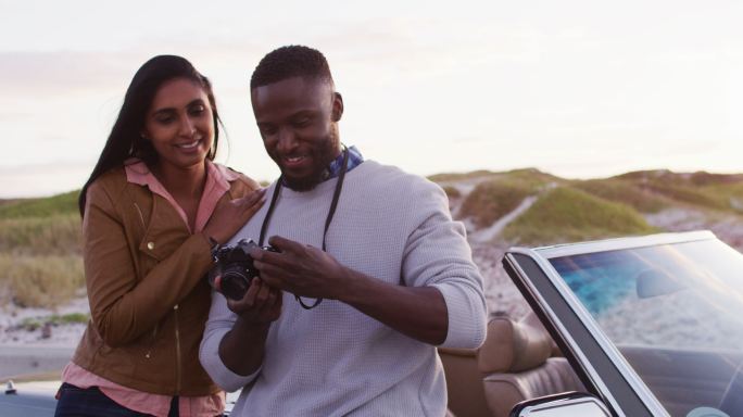一对非洲裔美国夫妇站在敞篷车附近用数码相机拍照