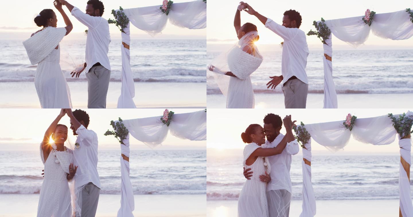 相爱的非裔美国人结婚，微笑着在日落时分的海滩上跳舞