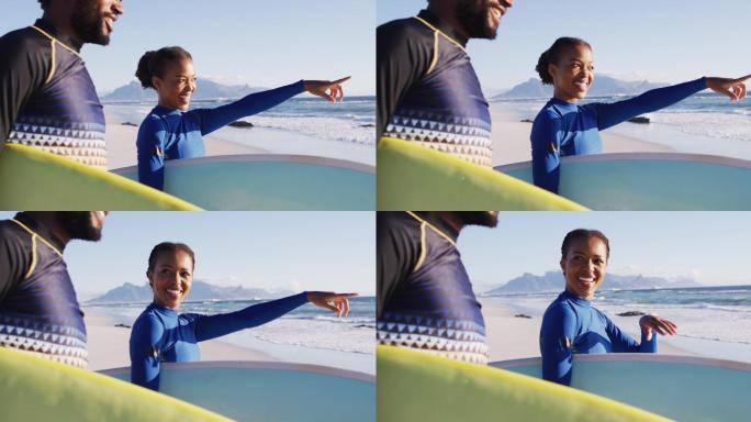 一对非洲裔美国人在沙滩上一边聊天一边拿着冲浪板