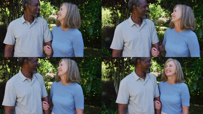 Diverse senior couple walking in their garden arm 