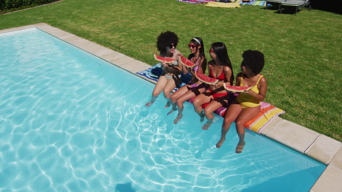 俯瞰一群不同的女孩坐在水池边吃西瓜