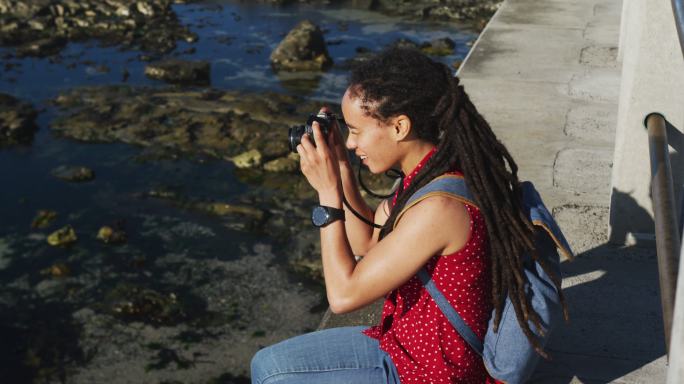一位非裔美国妇女坐在海边的长廊上拍照