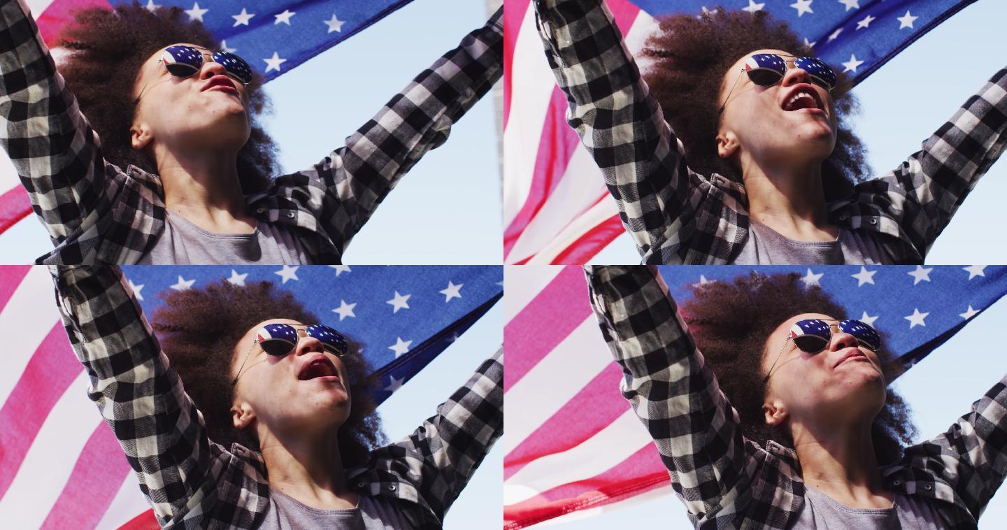 一位戴着太阳镜的非裔美国妇女在空中举着美国国旗