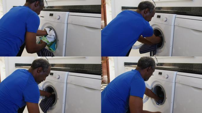 非洲裔美国老人把脏衣服放进家里的洗衣机里