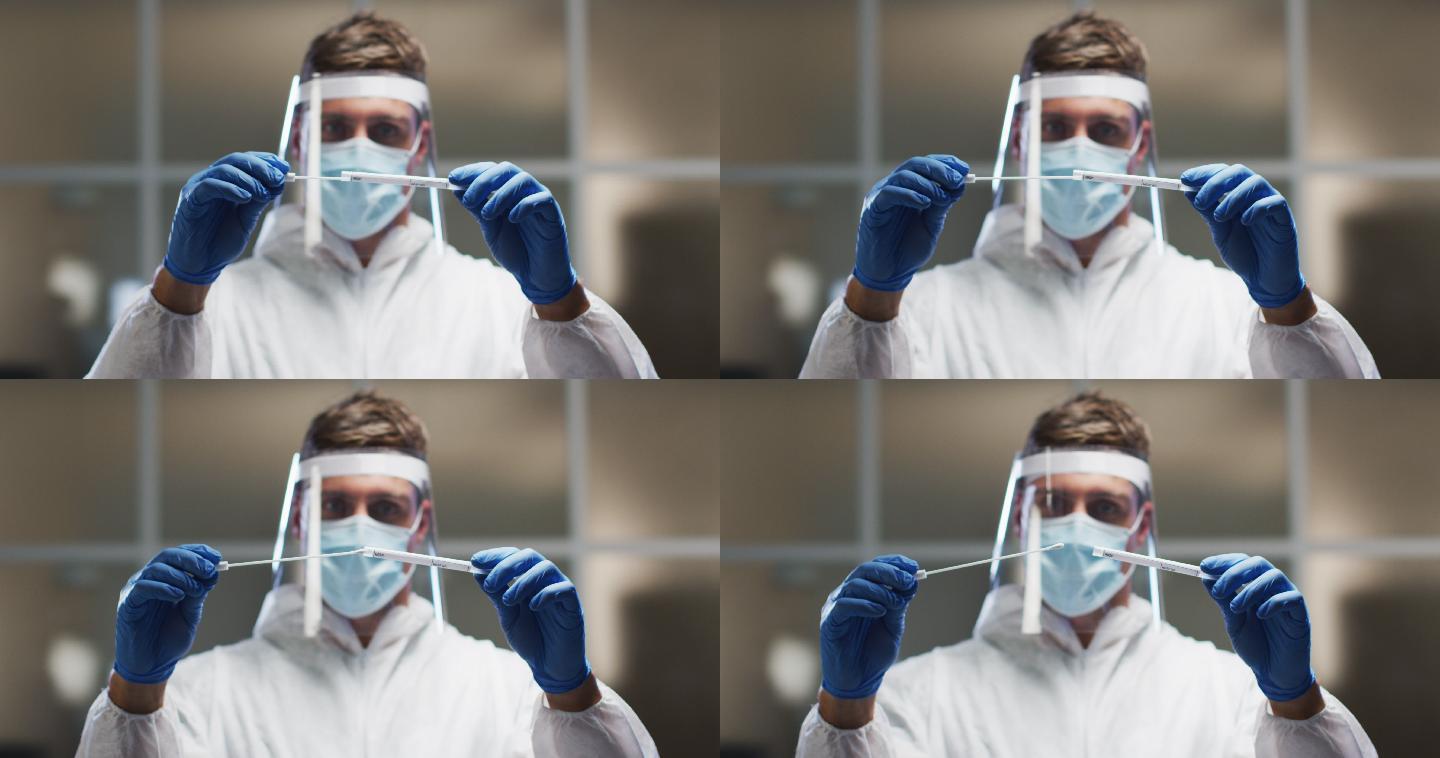 白人男性医务工作者穿着防护服和面罩在实验室检查dna拭子