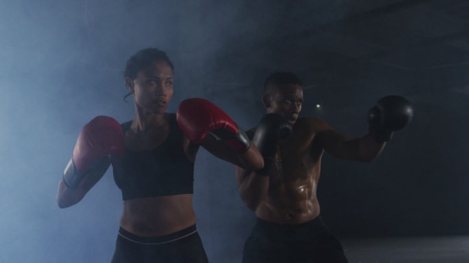 非洲裔美国男人和女人戴着拳击手套在空房间里训练投掷拳头